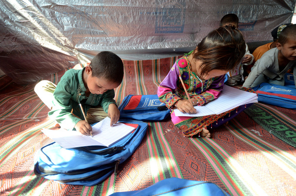 Afghan children seen learning in a makeshift school inside a tent. Al-Khidmat Foundation (AKF) established a tent village for flood-affected Afghan refugees at Hassan Khel, district Charsadda. The houses of 180 Afghan refugees residing in Hassan Khel an adjacent locality of Sar Daryab were destroyed in the recent flood.