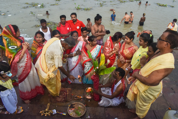 Hindu priests perform prayers in front of a banana tree trunk as part of a ritual (Nabapatrika) on the banks of the Ganges river during the Durga Puja festival in Kolkata.