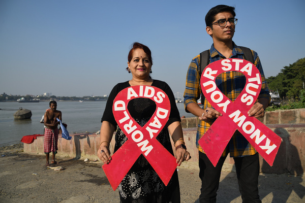 A voluntary group organises a prevention against AIDS campaign while holding red bands at riverbank of the Ganges ahead of World AIDS Day.