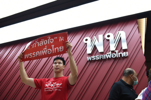 a man party supporter wearing a red shirt, holding up a sign asking the party to withdraw from joining the government led by the Parade Move Forward Party to form the government, at Pheu Thai Party Headquarters, New Petchburi Road, Bangkok, on May 28, 2023.