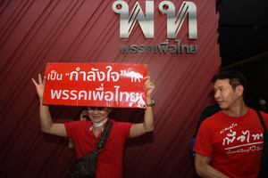 party supporter wearing a red shirt, holding up a sign asking the party to withdraw from joining the government led by the Parade Move Forward Party to form the government, at Pheu Thai Party Headquarters, New Petchburi Road, Bangkok, on May 28, 2023.