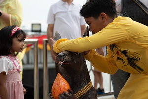 September 24, 2023 - A boy whispers a blessing into a mouse's ear. Belief is prayer. Please help bring your wishes to Lord Ganesha, the 16th Shree Ganesha Festival, into the Chao Phraya River at Bhumibol Bridge, Rama 3 Road, Bangkok, Thailand.