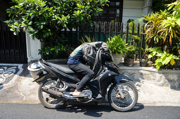 A man resting on a motorbike wearing a jacket to block the sun's rays. At 13.00 WIB the hot temperature in Malang City reached 36 degrees Celsius. Based on data from the Meteorology, Climatology and Geophysics Agency, Indonesia will experience heat for one week with a temperature of 37 degrees Celsius.