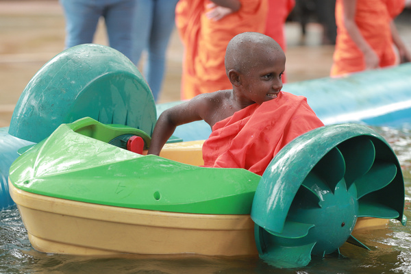 A Buddhist novice monks ride boats at Viharamahadevi Public Park in Colombo on September 29, 2023.
