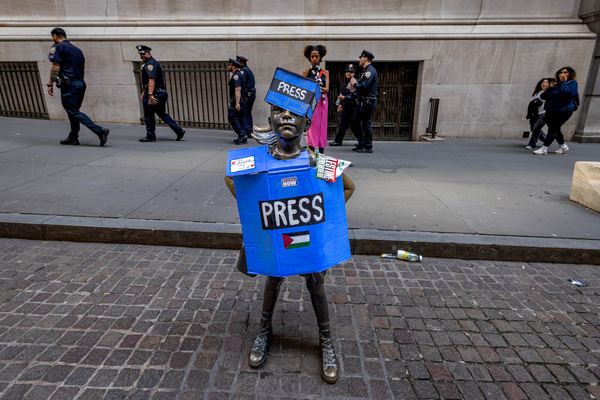 The Fearless Girl Statue is outfitted with Pro-Palestine Press paraphernalia during a Palestine protest outside of the New York Stock Exchange (NYSE).