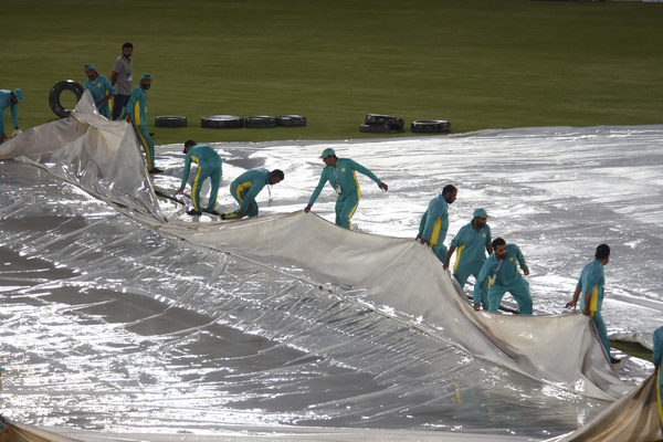 Pakistan's match umpires Ahsan Raza (R) and Aleem Dar (2L) inspect the ground next to the covered pitch during rainfall before the start of the first Twenty20 international cricket match between Pakistan and New Zealand at the Rawalpindi Cricket Stadium in Rawalpindi on April 18, 2024.