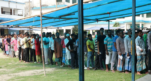 People stand in queues to cast their votes in the first phase of India's general election at a polling station near the India-Bangladesh border in Dinhata district of Cooch Behar in the country's West Bengal state on April 19, 2024.