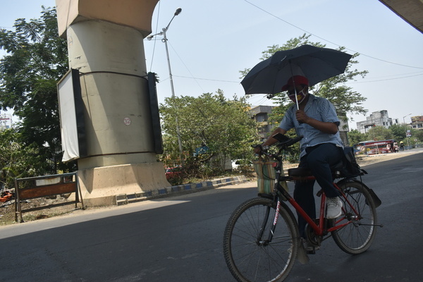A person is holding an umbrella while cycling a heat wave in Kolkata.
