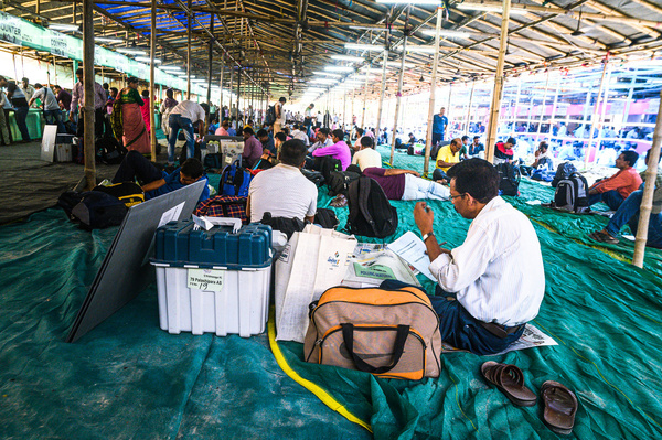 The polling officers and other election officials are called in the early morning to hand over the Electronic Voting Machines (EVM), ballot unit, and other election materials for voting to the distribution center. They are resting under the giant canopy after coming from far away; they will be transferred by car or bus to distant places after giving election materials for voting ahead of the fourth phase of voting in Nadia district in India's parliament general elections on 13th May. Those EVM machines are kept in high-security zones by the officials and polling officers look at the giant list board and check their polling destinations at Tehatta, West Bengal; India on 12/05/2024.