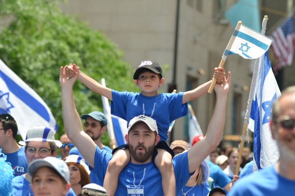Participants march while holding flags along Fifth Avenue in New York City during the annual Israel Day Parade.