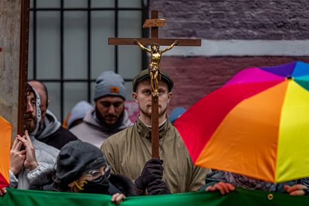 A man holding a crucifix prays behind the umbrellas of counter-protesters during an anti-abortion faith group's protest in front of Planned Parenthood.