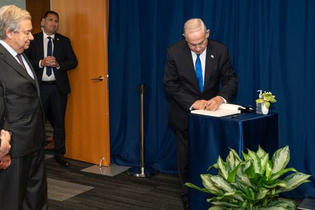The Secretary-General Antonio Guterres watching Prime Minister of Israel Benjamin Netanyahu signing a guest book with his own pen at the UN Headquarters.