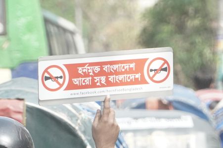 A man rides on a motorbike as he holds a placard says “ Horn free Bangladesh, more healthier Bangladesh” on a street in Dhaka, Bangladesh.