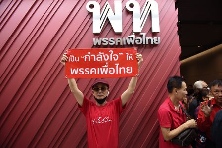 party supporter wearing a red shirt, holding up a sign asking the party to withdraw from joining the government led by the Parade Move Forward Party to form the government, at Pheu Thai Party Headquarters, New Petchburi Road, Bangkok, on May 28, 2023.
