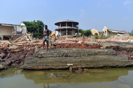 A person is standing in front of a damaged hotel by a natural disaster, made in the middle of the sea beach in Mandarmani, East Medinipur.