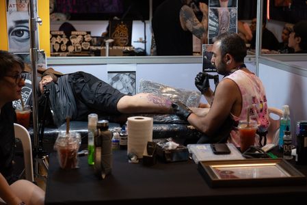 A tattoo artists making tattoo painting a man body in the Land of Ink Bangkok Tattoo Convention in ChangChui Creative Park, Bangkok on December 2, 2023.