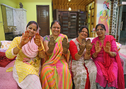 Indian women pose for photographs after applying Heena on their hands on the occasion of Sinjara festival ahead of Sawan Teej in Beawar.