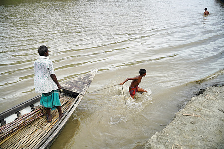 A child is seen to pull the boat with a passenger in the Ichamoti river which is mostly disappearing due to the heavy flooding of the Padma river near Manikganj, Dhaka, Bangladesh on August 29, 2021.