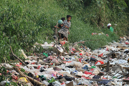 Children play on the edge of the Busa River where the river is filled with a 200-meter-long pile of plastic waste in Setia Mekar Village, North Tambun, Bekasi, West Java, Indonesia. Residents around this river have complained about piles of garbage that have not been transported, and hope that this waste will be immediately transported from the river by the local government or related parties.