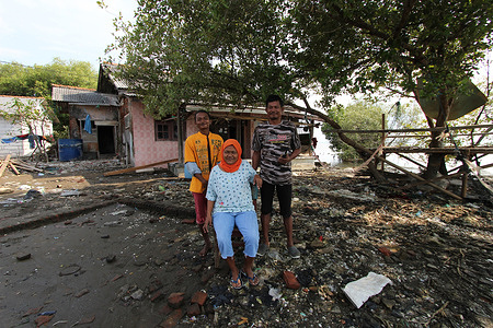 The portrait of the family of Sartain (49), who is still registered as a resident of Jakarta, is photographed in front of a damaged house belonging to a relative of his wife which is now occupied with his family since 2 years ago who had been left behind due to erosion by the sea in Pantai Mekar Village, Muara Gembong, Bekasi, West Java, Indonesia. Dozens of houses in this village have been washed away by sea water during abrasion since 2007. Global warming raises sea levels, thousands of islands are threatened with disappearance and sinking, including in Indonesia.