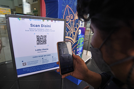 Visitors scan a barcode (QR code) using the 'care for protection' application before entering the Palu Grand Mall Shopping Center, Central Sulawesi. The mall has started testing the use of the application for shopping center visitors. This application is known to function to share community location data while traveling so that contact history tracing with Covid-19 sufferers can be carried out.