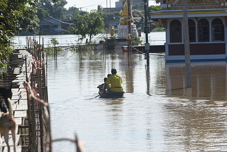 a man rowing a boat send believers to make merit Inside Wat Kai Tia, that flooded Sam Khok District, Pathum Thani Province on October 24, 2021.