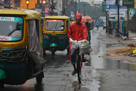 A man wearing rain coat riding on his bicycle during heavy rainfall due to Cyclone Jawad in Kolkata.