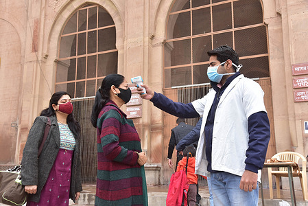 A health worker uses a temperature screening device on a tourist in wake of rise in Omicron variant of the coronavirus at Junagarh fort in Bikaner.