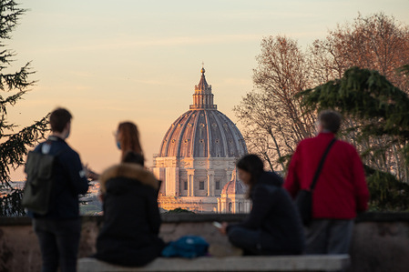 Tourists observe St. Peter's Dome at sunset from Piazzale Garibaldi on Janiculum Hill, on December 31, 2021
