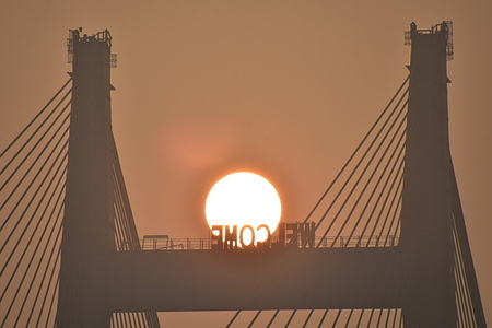 The rising sun amid smog through the Vidyasagar Setu (bridge) across the Ganges on the first day of Gregorian calendar year 2022.