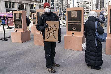 The Daily Show Monuments for Heroes of the Freedomsurrection on anniversary of insurrection at the Capitol on January 6, 2021, seen on pedestrian plaza next to Madison Square Park. A man is holding signs expressing his opinion at the monuments. The 8 monuments featured Rudy Giuliani, Tucker Carlson, Steve Bannon, Senator Josh Hawley, Senator Ted Cruz, U. S. Representative Lauren Boebert, U. S. Representative Marjorie Taylor Greene, former President Donald J. Trump. All monuments were designed to look like tombstones.