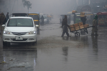 Pakistani motorists make their way during heavy first spell winter rain falls in Lahore.