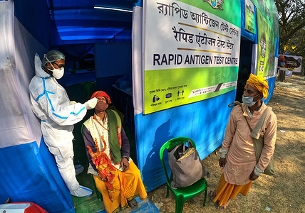 A health worker wearing PPE (personal protective equipment) performs a Covid-19 coronavirus screening of pilgrims at a transit camp ahead of the upcoming annual Gangasagar Mela or annual religious fair at the Sagar Island, in Kolkata on January 8, 2022.