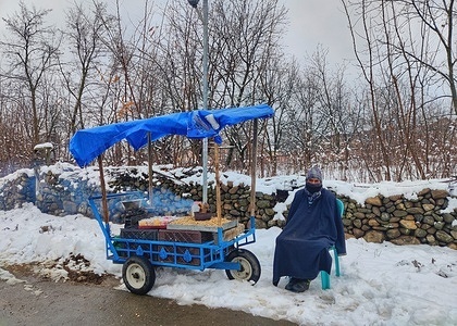 A Kashmiri man sells dried fruits on the road during fresh snowfall some 80 kilometers from capital city of Srinagar.