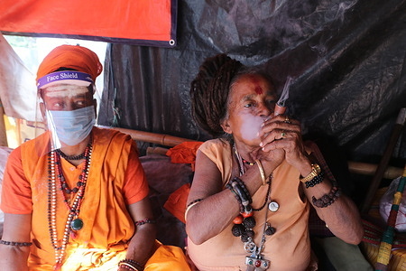 A Hindu woman Sanyasin or Sadhu puffs marijuana at a transit camp on the way to Gangasagar in Kolkata
