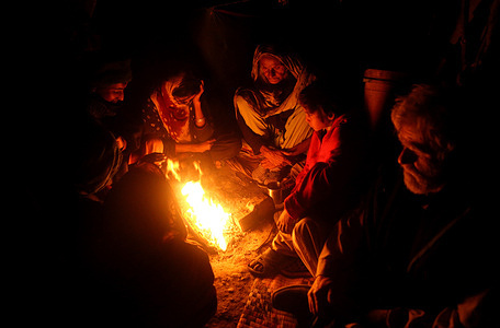 A gypsy family including children and women's sit near the fire in there ordinary home during the cold nights in the city at Jamshoro road side.