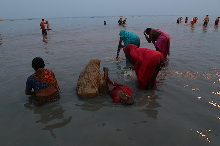 Hindu devotee takes a holy dip in the Bay of Bengal on the occasion of Makar Sankranti at Sagar Island, around 150 kms south of Kolkata on January 14, 2022.