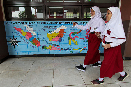 Two elementary school students not wearing masks pass in front of a closed elementary school classroom with a mural of a map of the sovereignty and national jurisdiction of the Republic of Indonesia, in the Cipinang area, East Jakarta, Indonesia. A number of students and teachers at Jakarta schools were exposed to Corona, one of them was the suspected Covid-19 Omicron. As a result, the Provincial Government of the Special Capital Region of Jakarta has temporarily closed dozens of schools that carry out face-to-face learning (PTM) with a limited capacity of 100 percent for the time being. A number of schools have decided to change the method of learning from home.