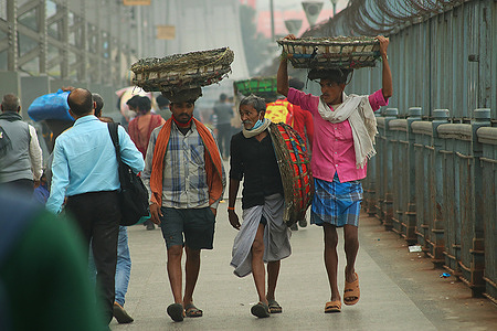 Labors walk while crossing the Howrah Bridge a winter morning in Kolkata on21 January 2022.