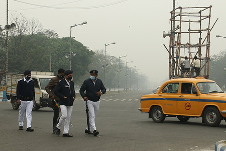 Police personnel walk in the streetamid smoggy conditions in Kolkata, West Bengal