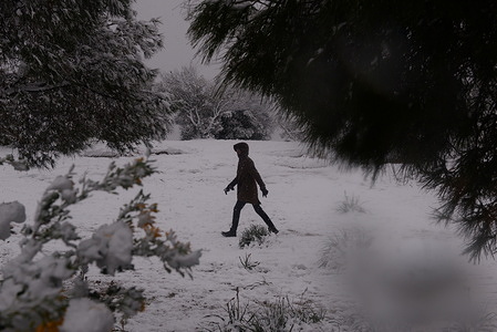 Woman walks during the snowfall in Athens.