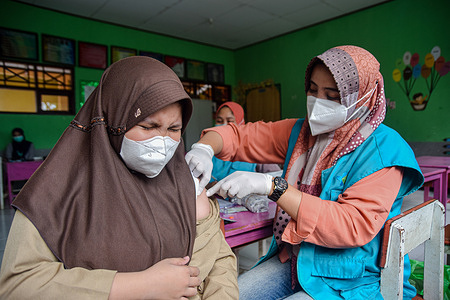 A child aged 6-11 years receiving a dose of the Sinovac Covid-19 vaccine at a school in the city of Soppeng. the local government targeted 18,621 children who were targeted for vaccination.