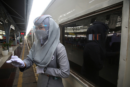 A train stewardess wears gloves, a mask and a face shield at Pasar Senen Station, Jakarta. The surge in the number of passengers at Pasar Senen Station has started to be seen a week before Eid and is expected to continue to grow until D-2 Eid al-Fitr. The high enthusiasm of the community in traveling, PT KAI operates a number of additional trains in order to welcome the Eid al-Fitr holiday.