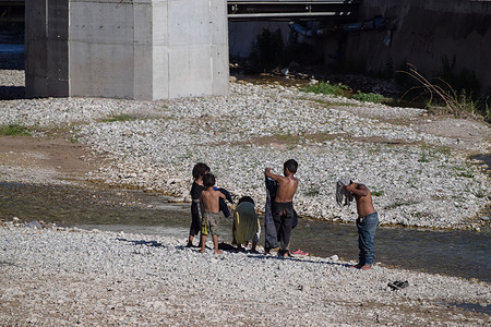 Romani children bathing in the river Glafkos below the highway bridge near the port of Patras, as the nearby camp of Romani people has no access to clean water and sanitation.