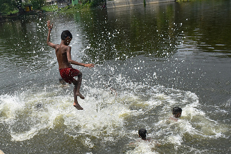 A boy jumps into a pond to cool off on a hot summer day on the outskirts of Kolkata.