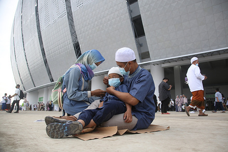 A father corrects the position of his child's mask after the Eid prayer 1443 Hijri at the Jakarta International Stadium (JIS) in Tanjung Priok, Jakarta, Indonesia. For the first time JIS was used for Eid prayer, it was a historic moment. Because it was held in a new place and marked a victory after two years of being affected by the Covid-19 pandemic.