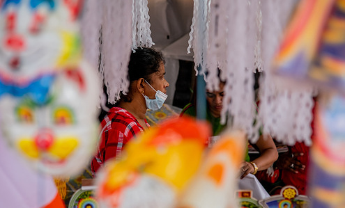 Sri Lankan vendors hang colourful masks for sale at a temporary shop ahead of before the Vesak Day in Colombo on May 14, 2022. Sri Lankan Buddhists are preparing to celebrate Vesak, which commemorates the birth of Buddha, his attaining enlightenment and his passing away on the full moon day of May which falls on May 15 this year.