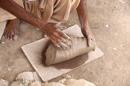 A potter is busy in his daily work making mud items.