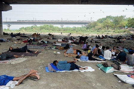People take shelter under a bridge near the Yamuna River bed on a hot summer afternoon in New Delhi.
