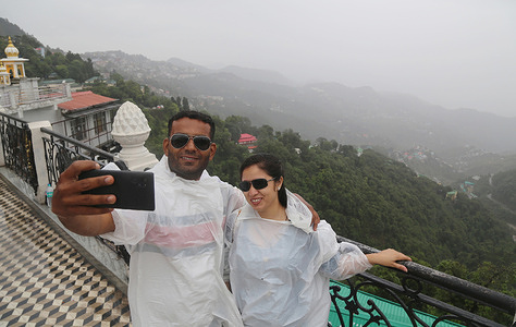 An Indian couple takes selfie as they enjoying first rain of monsoon in Mussoorie. Tourists from across the country arrives here to celebrate weekend in summer season.